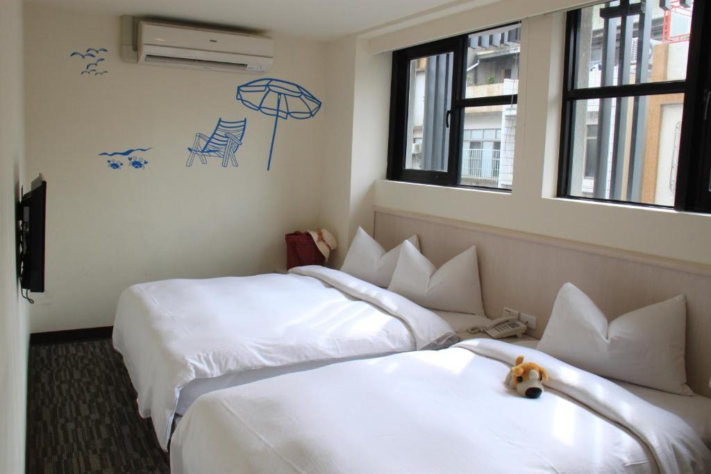高雄世纪旅店的两间位于酒店客房的床,中间有泰迪熊
