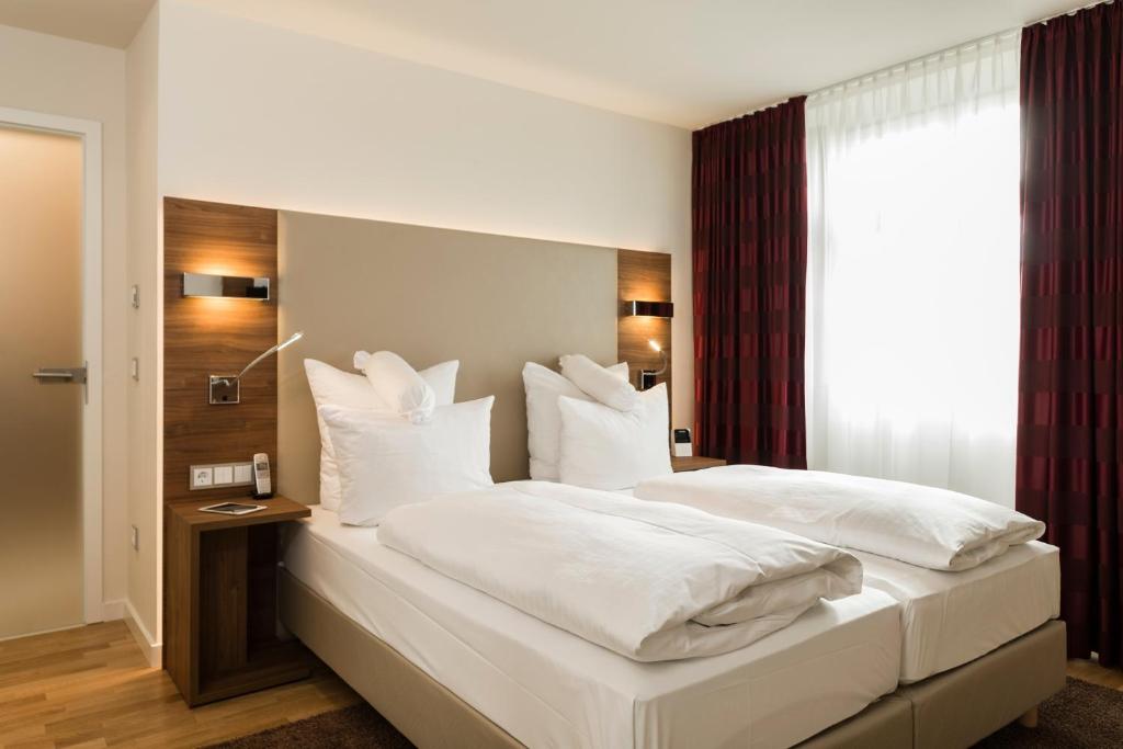 莱茵河畔路德维希港Living Apartments Ludwigshafen的卧室配有白色大床和白色枕头