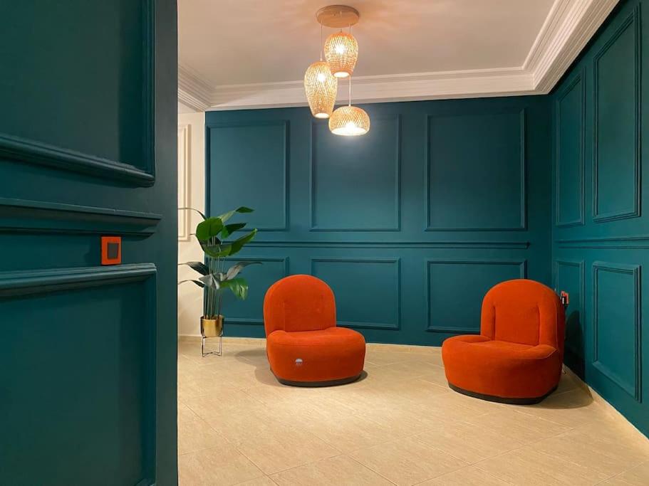 拉巴特Appartement au cœur de Rabat的蓝色墙壁的房间里设有两把橙色椅子