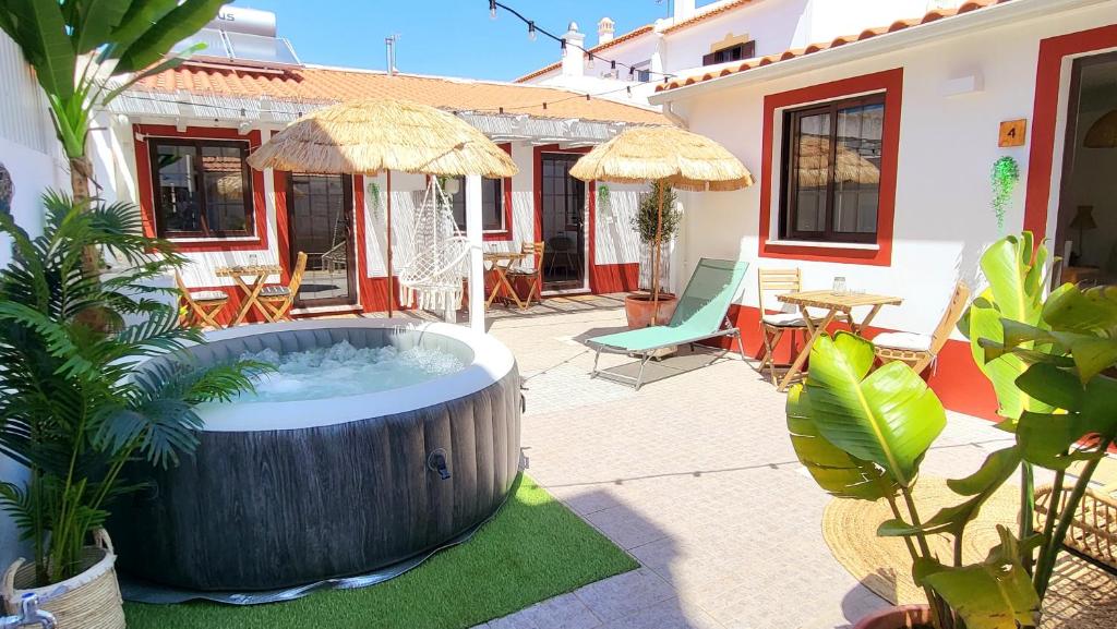 米尔芳提斯城Cantinho de Milfontes Jacuzzi的庭院内的热水浴池,配有椅子和遮阳伞