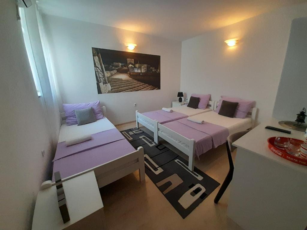 莫斯塔尔Pansion Ponte的客房配有两张带紫色枕头的床。