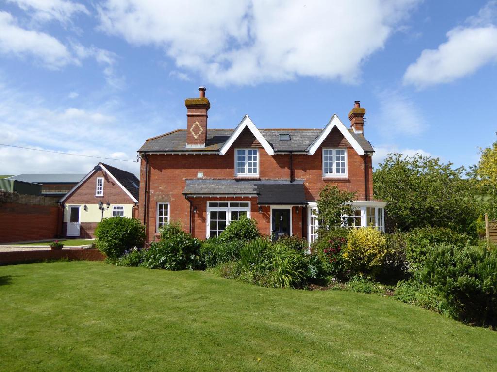 韦茅斯Pump Cottage的一座带绿色庭院的大型红砖房子