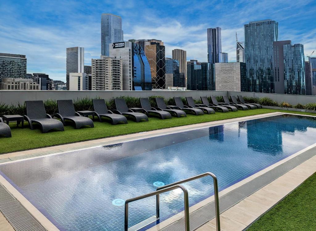 墨尔本墨尔本温德姆酒店的一座建筑物屋顶上带椅子的游泳池