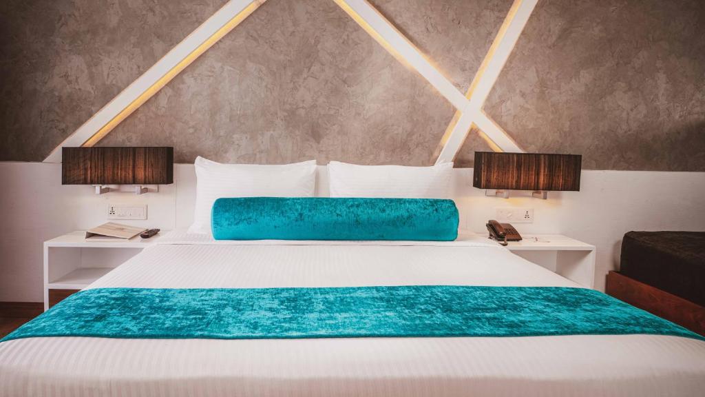 尼甘布卡米洛特海滩酒店的一间卧室配有一张白色的床和蓝色的毯子