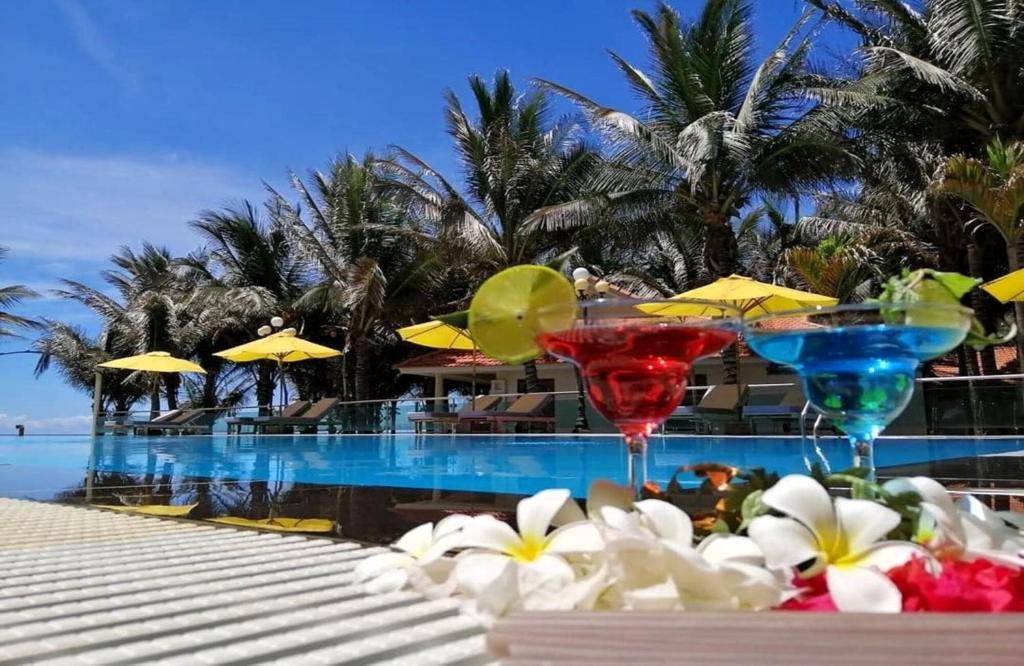 美奈Saigon Emerald Beach Resort的两个马提尼玻璃杯坐在游泳池旁