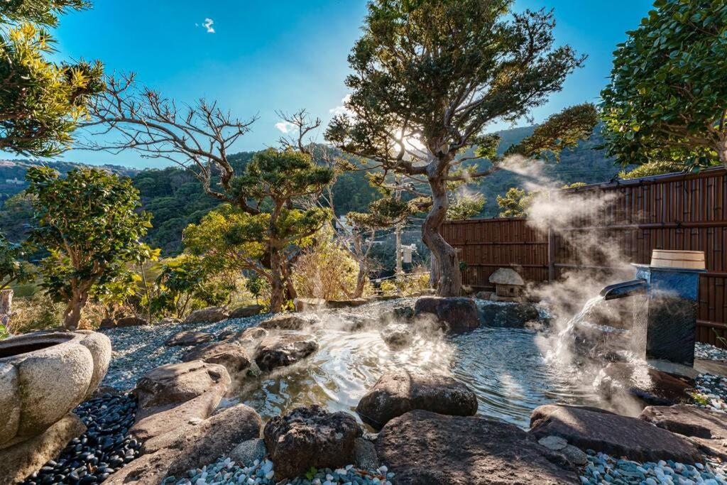 热海VILLA ATAMI -Nagomi-的花园中的一个喷泉,花园内有岩石和树木