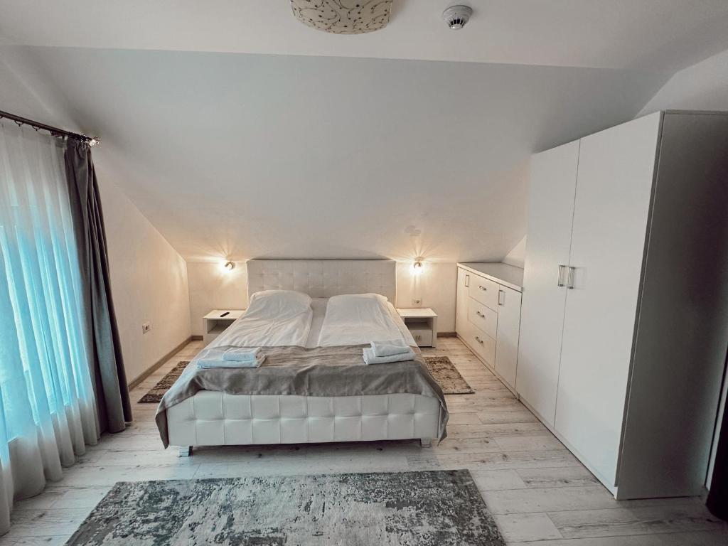 Vicovu de JosCazare Vicoveancaa的卧室设有白色的床和大窗户