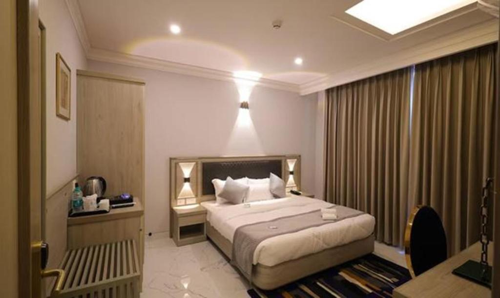 诺伊达FabHotel Prime Hampton By IC's的酒店客房配有一张床、一张书桌和一张四柱床