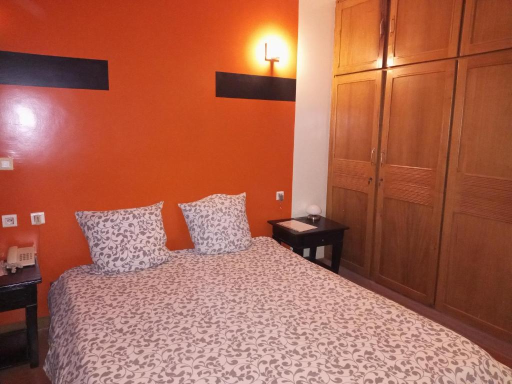 瓦加杜古Le ZaNaLi Hotel的一间卧室配有一张橙色墙壁的床
