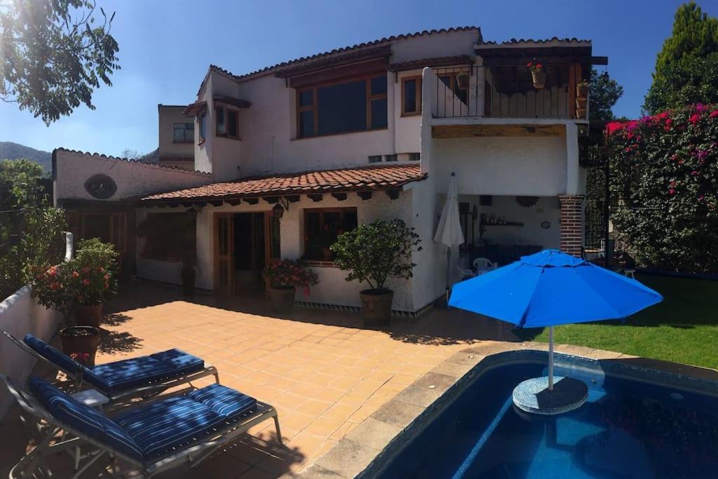 迪坡斯特兰Acogedora Villa con alberca climatizada en el centro de Tepoztlán的一座带游泳池和蓝伞的房子
