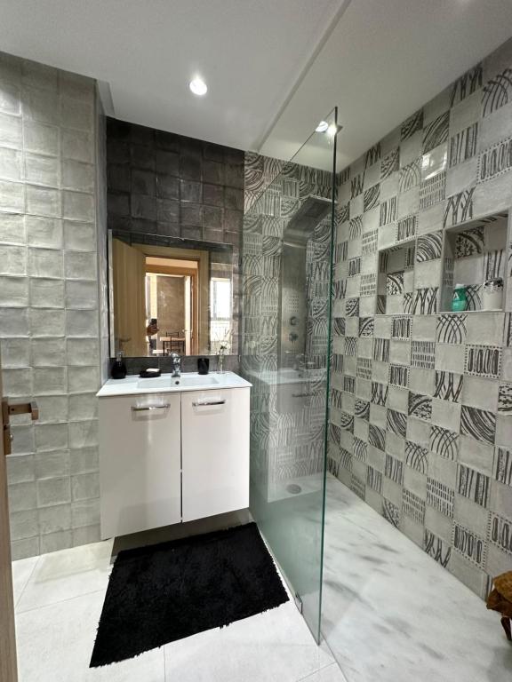 阿加迪尔Luxueuse appartement的一间带水槽和玻璃淋浴的浴室