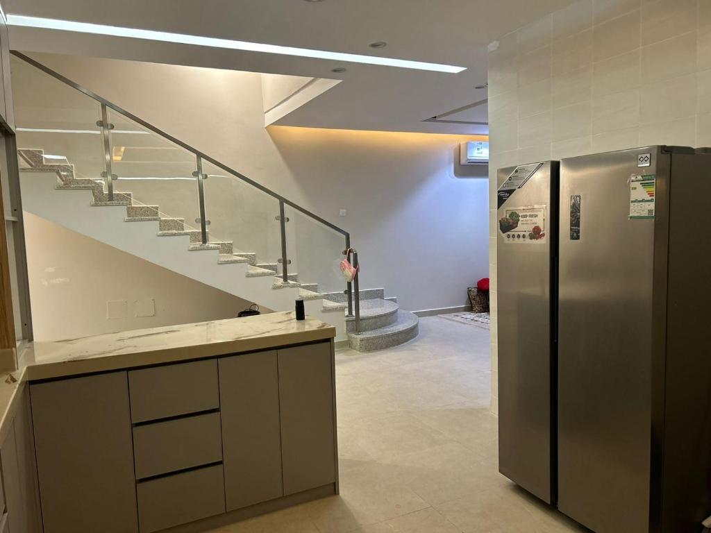 利雅德Riyadh Salman Villa فيلا的厨房设有楼梯和不锈钢冰箱