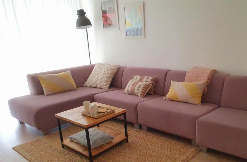 滨海卡特韦克't Hoekhuisje的客厅配有一张紫色沙发,配有一张桌子