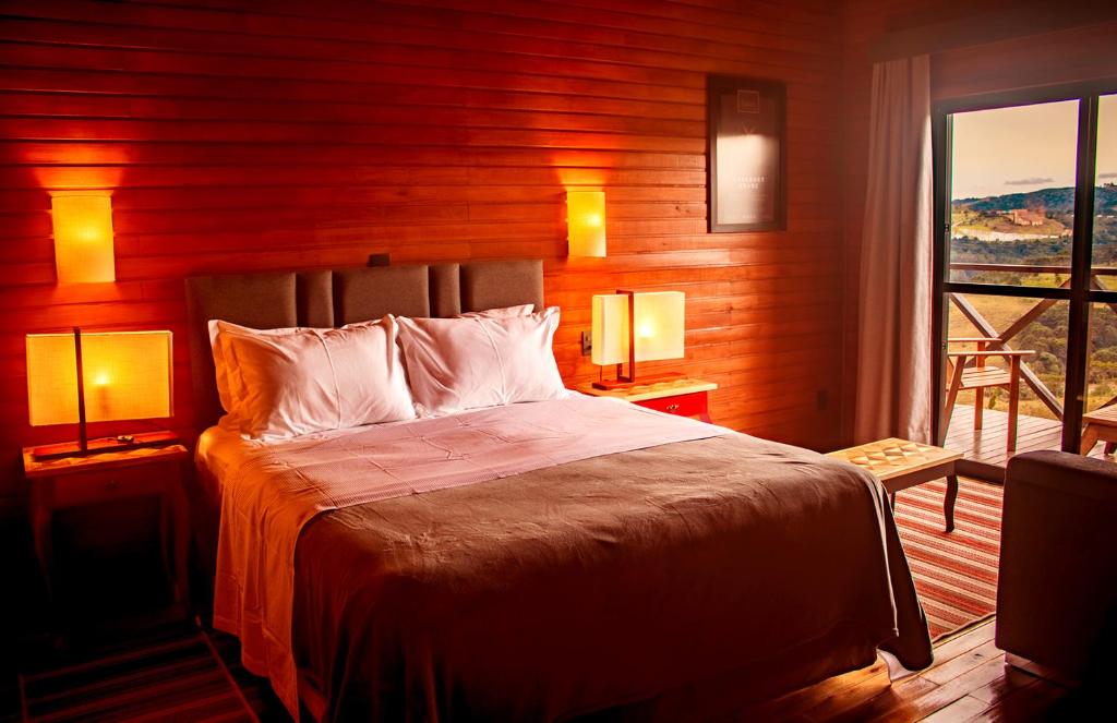 圣若阿金Vinícola D'alture - Cabana Casal -的一间卧室配有一张带两盏灯的床和一扇窗户。