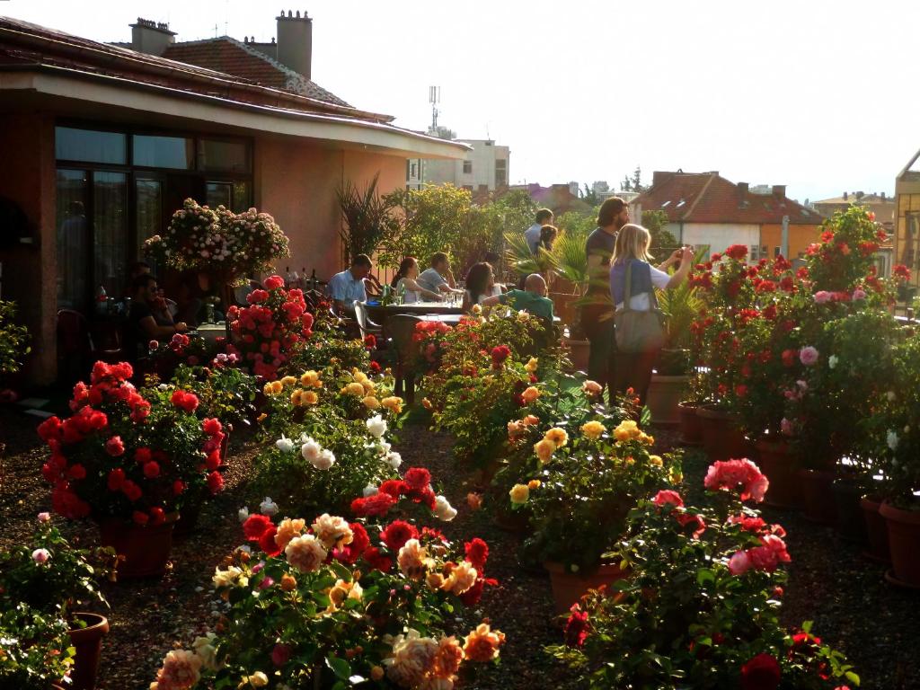 卡赞勒克Семеен Хотел РОЗА的一群人站在种满鲜花的花园中