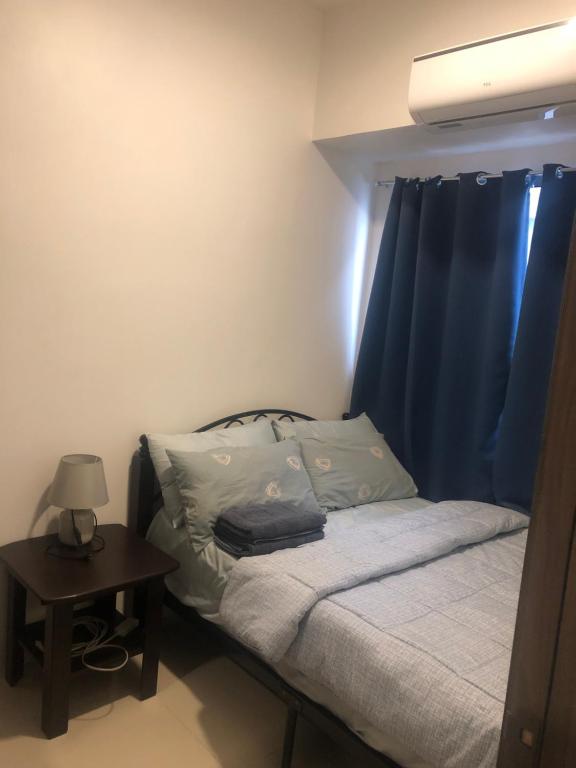 马尼拉Staycation的一间卧室配有一张带蓝色窗帘的床和一张桌子