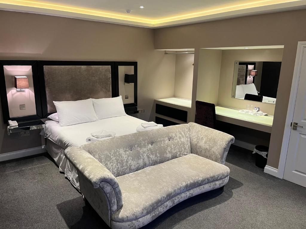 尼德姆马基特Limes hotel的一间卧室配有一张床、一张沙发和一面镜子
