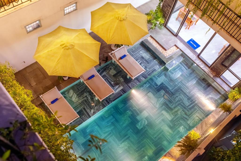 会安Tomorrow Boutique Villa Hoi An的享有带遮阳伞和椅子的游泳池的顶部景致
