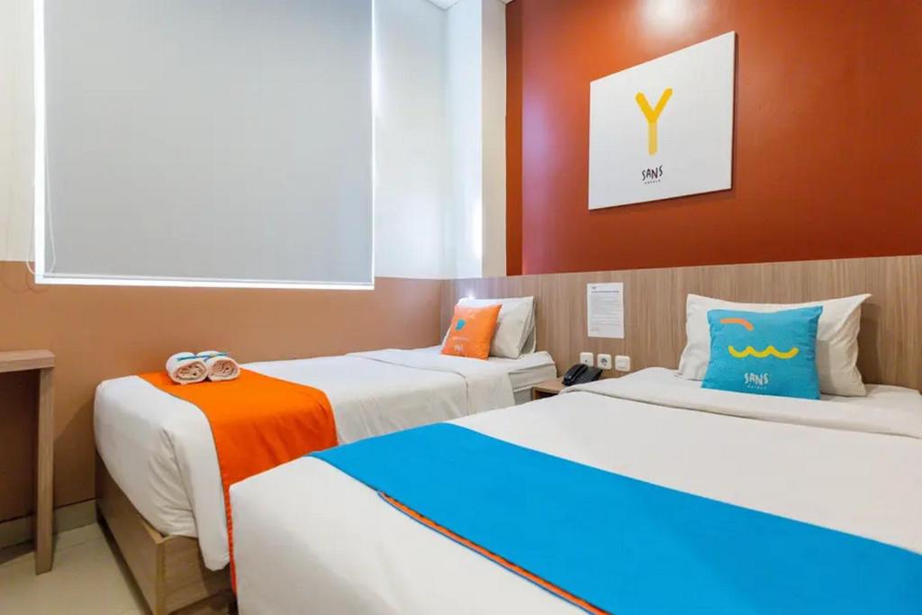 KrembanganSans Hotel Rajawali Surabaya by RedDoorz的一间客房配有两张橙色和蓝色的床