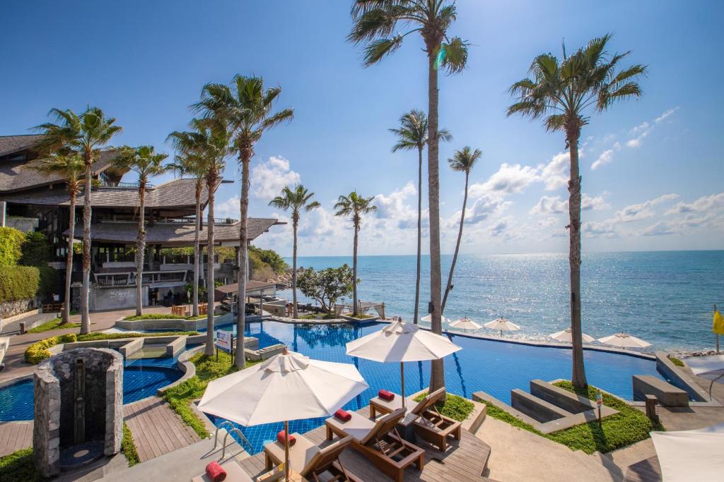 查汶Nora Buri Resort & Spa - SHA Extra Plus的一个带椅子和棕榈树的度假游泳池以及大海