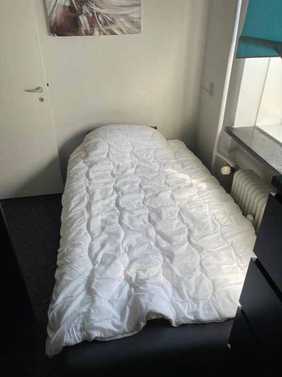 哥本哈根Nice room near airport的一张带白色棉被的未铺床