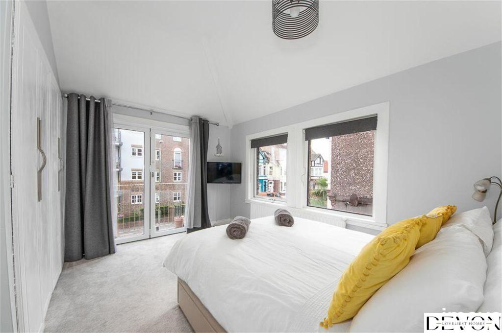 佩恩顿Loveliest Homes Paignton - Casa Marina - 3 bed, 2 bathroom house, balcony, parking的白色卧室,配有一张黄色毯子床