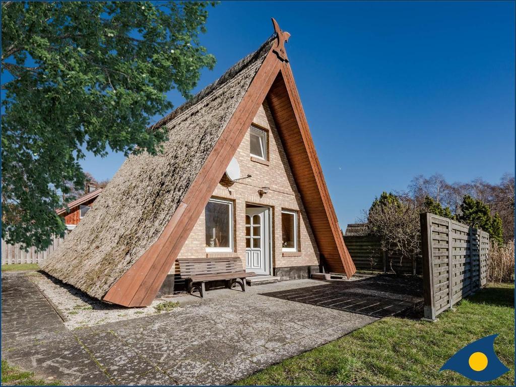特拉森海德Reetdachhütte im Birkenhain的茅草屋顶的小房子,带长凳