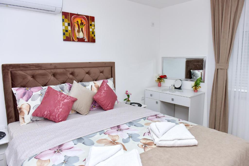 KuršumlijaApartmani Simić的一间卧室配有一张带粉色和紫色枕头的床