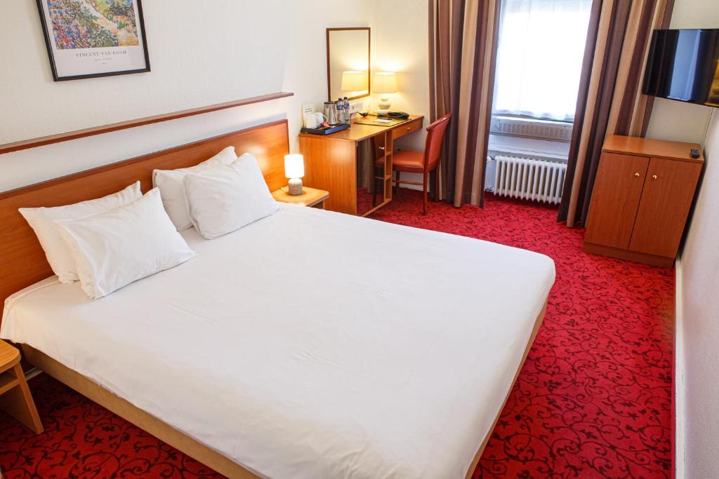 日内瓦阿斯托里亚酒店的酒店客房设有一张白色大床和一张书桌