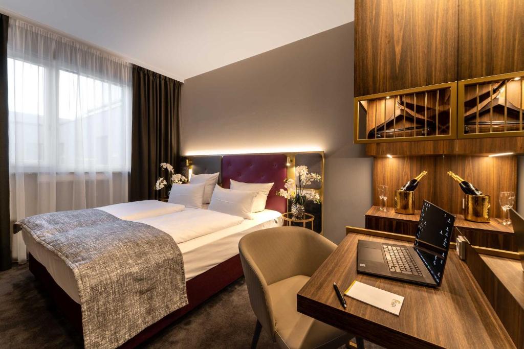 慕尼黑PLAZA Premium München的酒店客房配有一张床、一张书桌和一台笔记本电脑