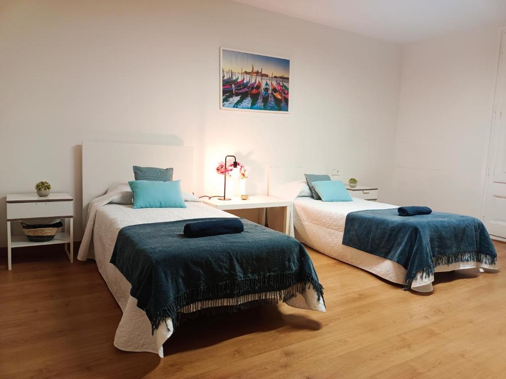 巴塞罗那By Cathedral Rooms的一间卧室配有两张带蓝色棉被的床