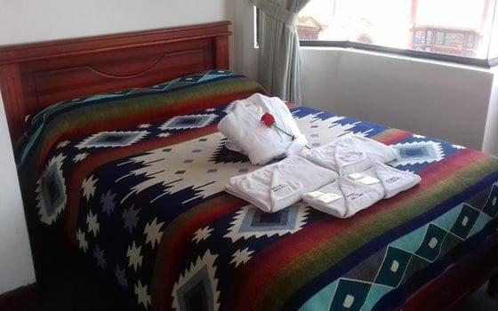 奥塔瓦洛Coraza Hotel的一张带色彩缤纷的被子和毛巾的床