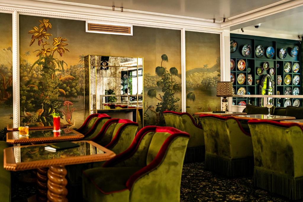 巴黎Hôtel Eldorado Paris的一间设有绿色椅子、桌子和绘画的餐厅