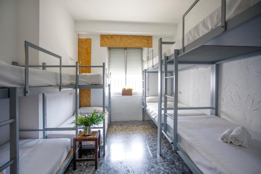 桑蒂蓬塞Italica Hostel的带4张双层床和走廊的客房