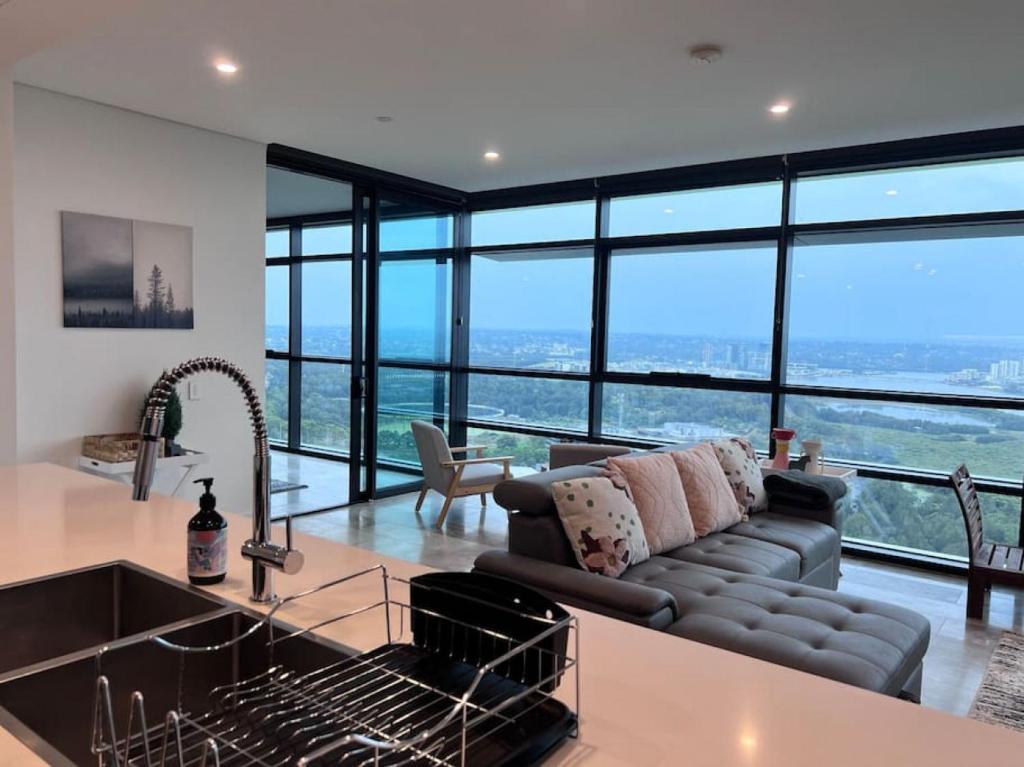 悉尼High Level Fabulous View 4Beds APT in Olympic Park的厨房以及带沙发和大窗户的客厅。