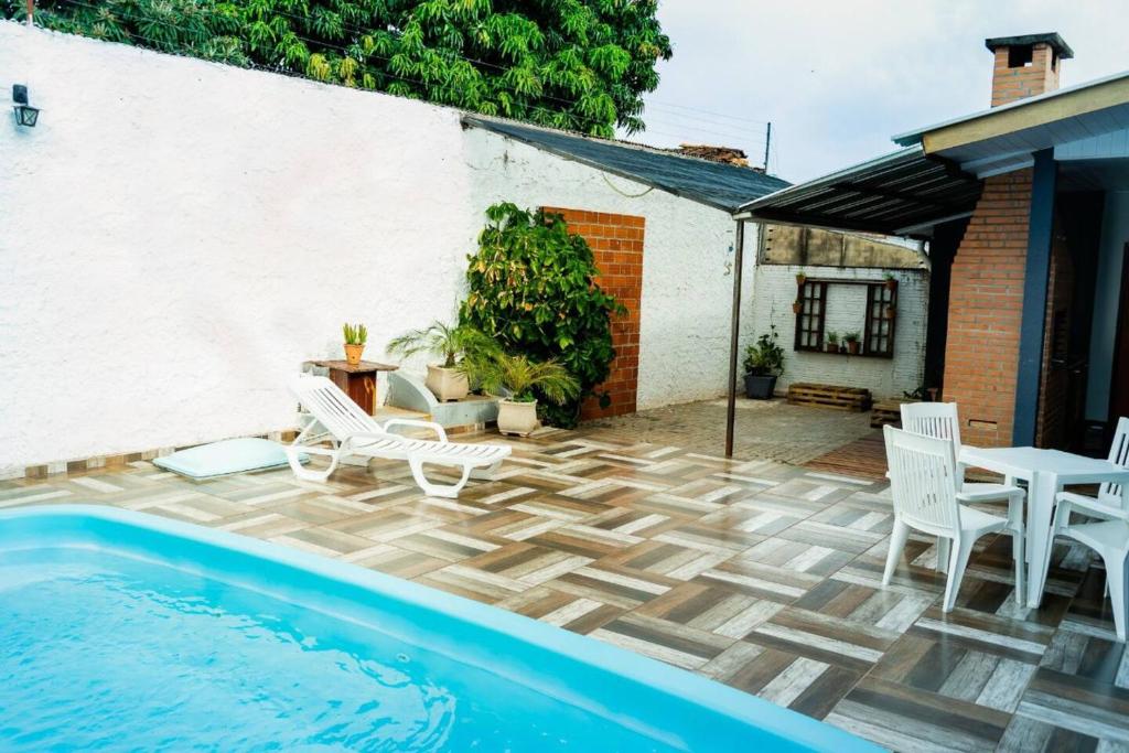 伊瓜苏Casa na Fronteira的庭院设有游泳池、椅子和桌子。
