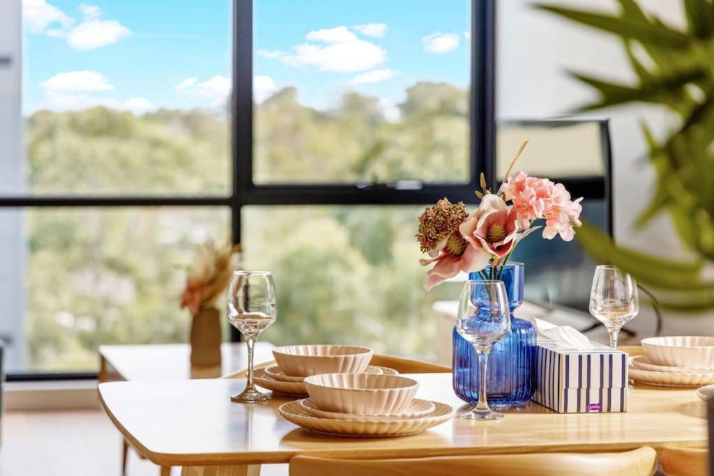 悉尼Adorable 2B Apt near Macquarie Uni的一张桌子,上面有盘子,蓝色的花瓶