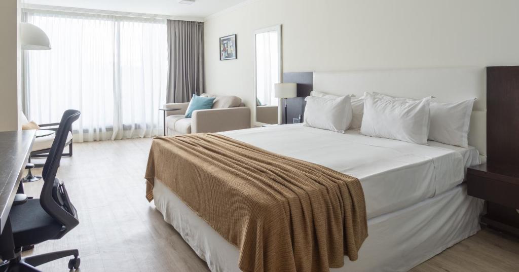 蒙得维的亚蒙得维的亚阿芙特酒店的酒店客房设有一张白色大床和一张书桌