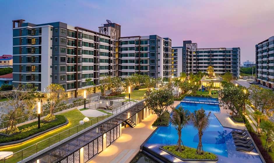 Ban Khlong Samrongsupalai city resort的一座大型公寓楼,设有游泳池和棕榈树