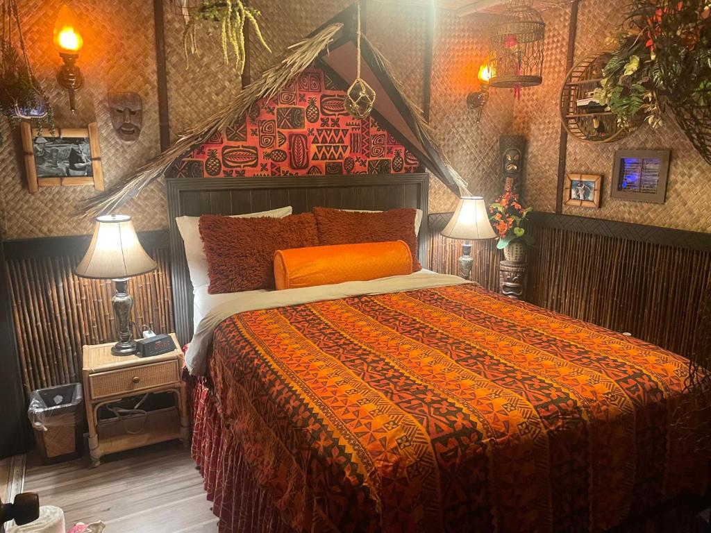 坦帕The Kondo Tiki的一间卧室配有一张带橙色棉被和两盏灯的床。