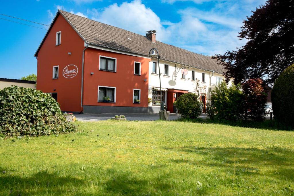 Breitscheid蓝哥祖尔荣酒店 的一座红色和白色的房子,有绿色的院子