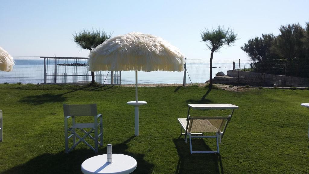 朱利亚诺瓦Agriturismo Frontemare的草上一张桌子和两把椅子及一把伞