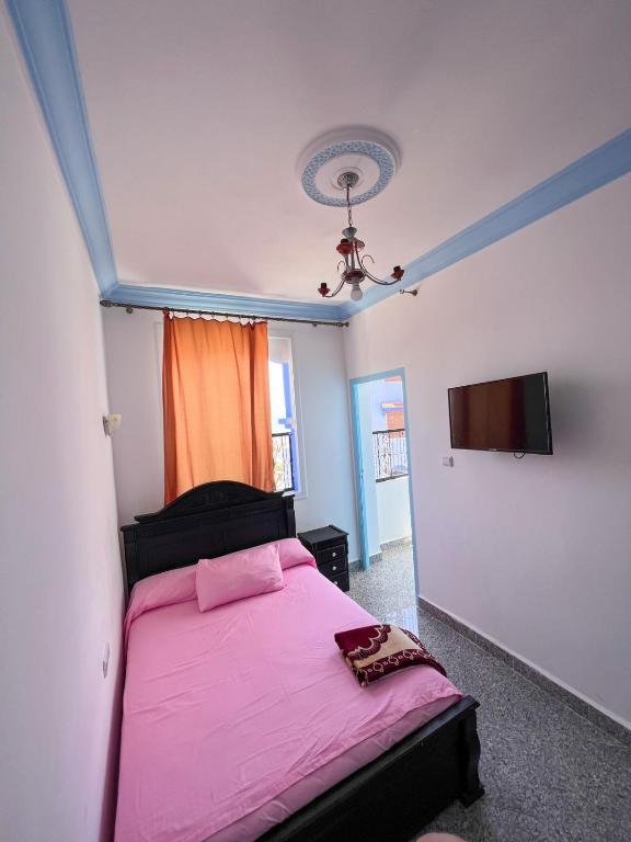 舍夫沙万Casa chaara的卧室配有粉红色的床和平面电视。