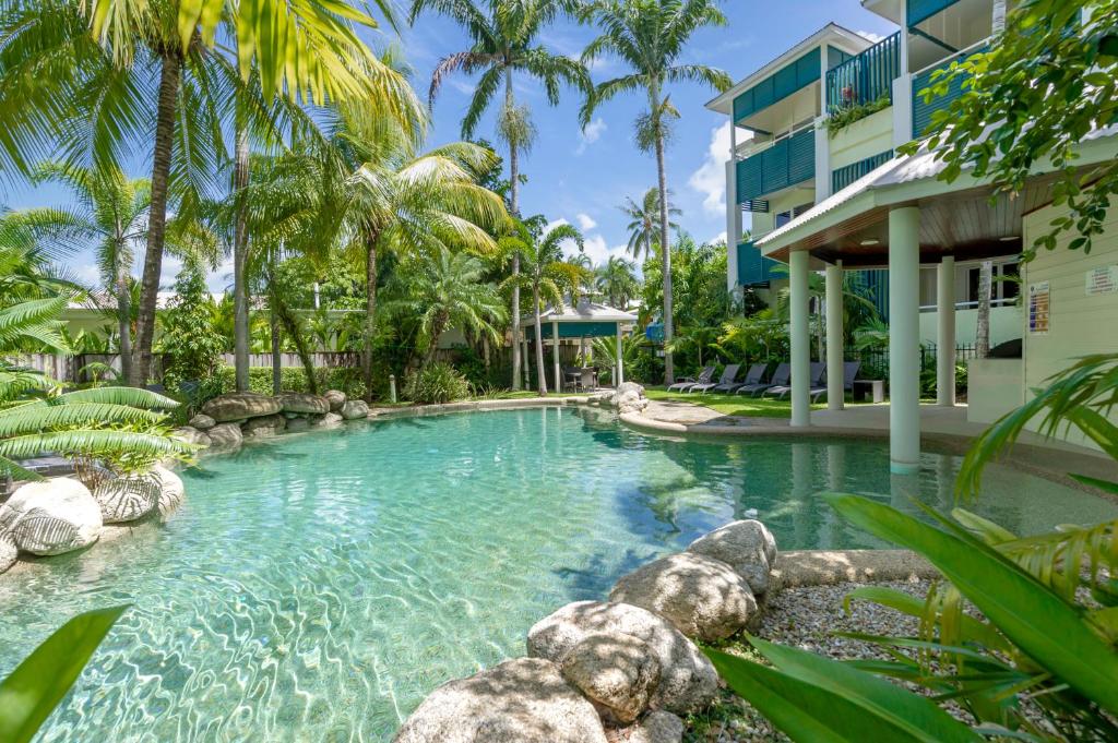 道格拉斯港游廊精品公寓酒店的棕榈树建筑前的游泳池
