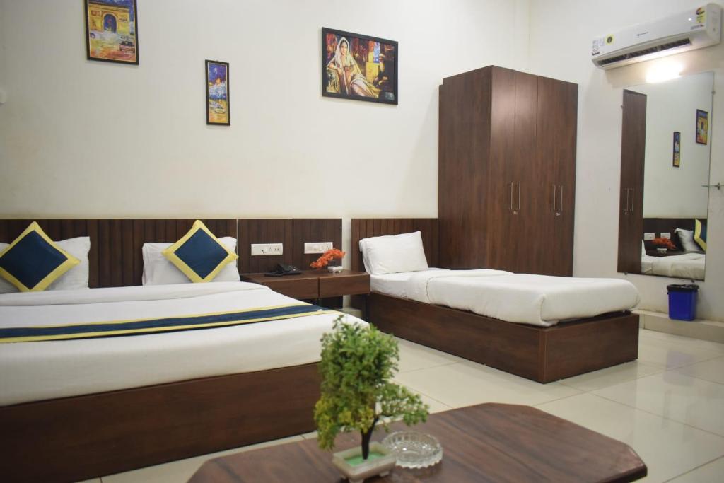 印多尔Hotel Lakshya Sheesh Mahal Indore的酒店客房设有两张床和一张桌子。