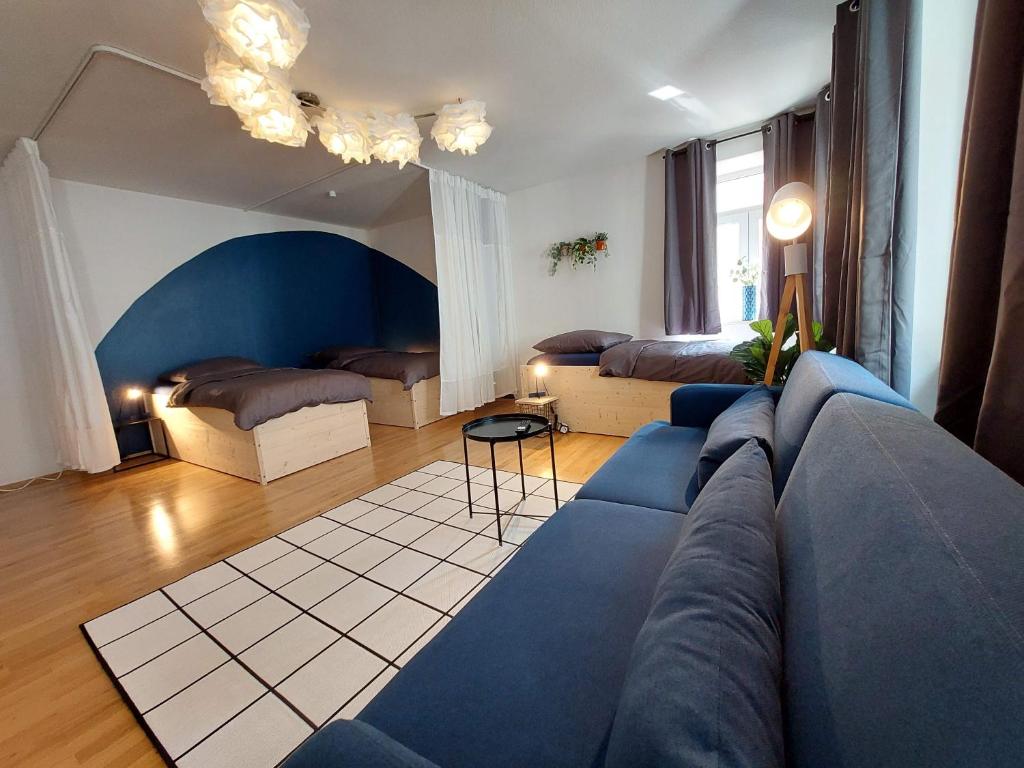 安贝格Viel Platz für Gruppen inkl. Waschmaschine, Hochstuhl und Playstation mitten in der Altstadt的客厅配有蓝色的沙发和两张床