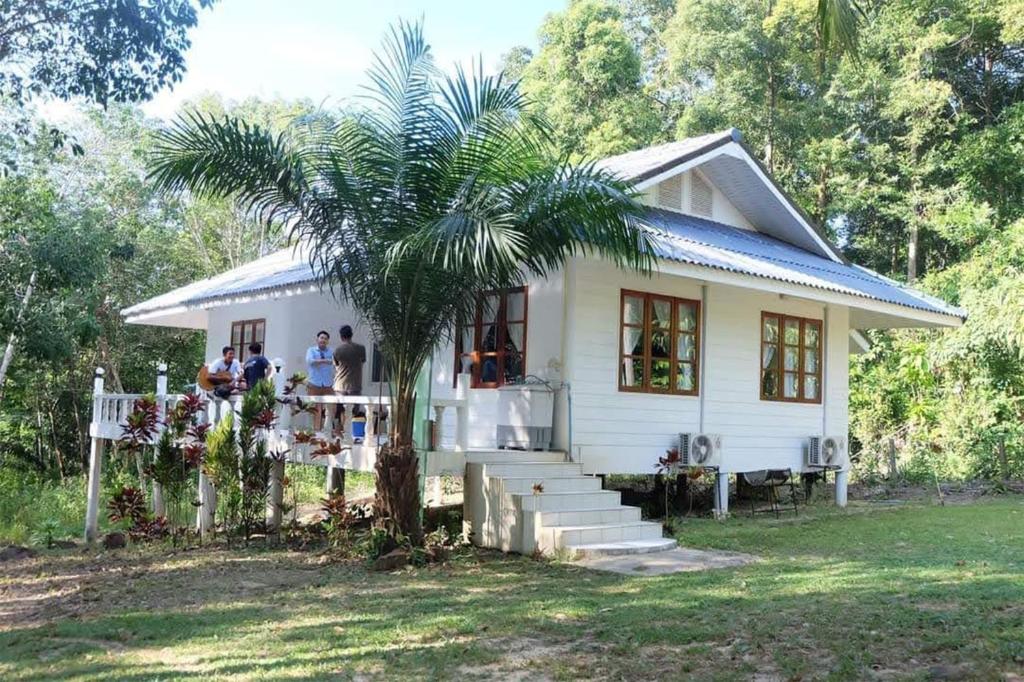 库德岛沽生活度假屋的一座白色的小房子,前面有一棵棕榈树