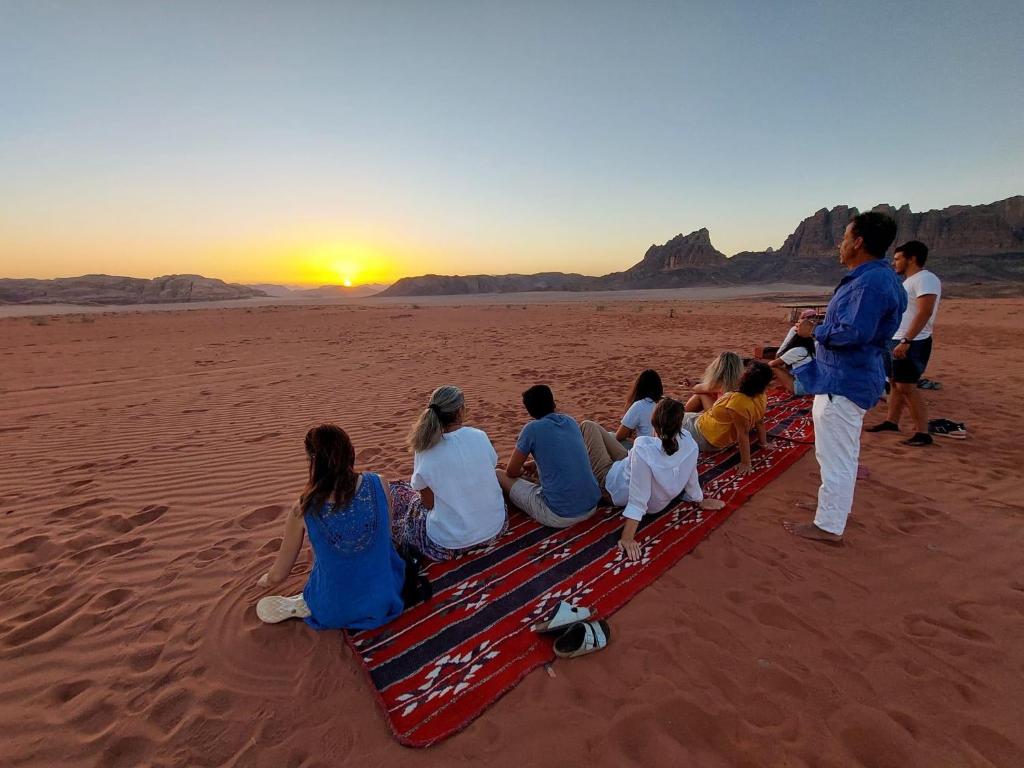瓦迪拉姆bedouin future camp的一群坐在海滩上的人,看着日落