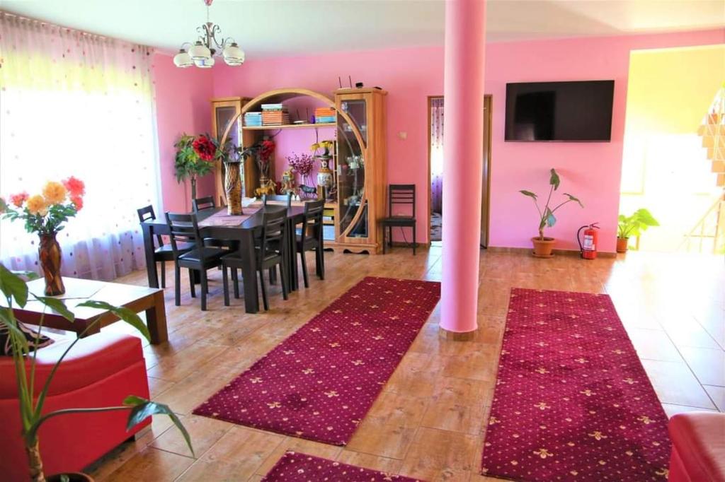 StoeneştiCasa de Vacanta Eva的粉红色的客厅,配有桌子和粉红色的柱子