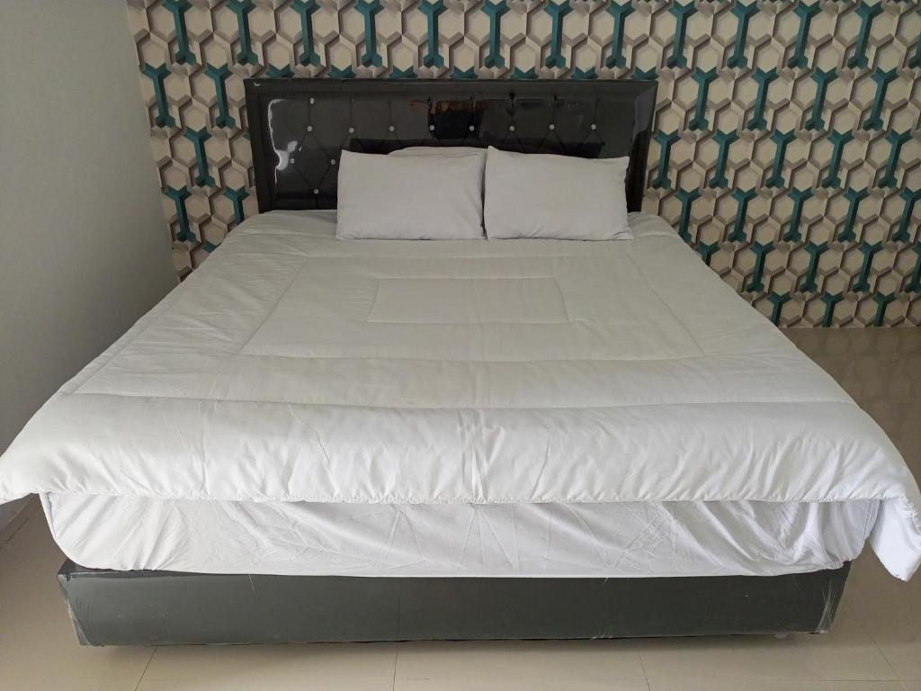 KaliandaPenginapan Lamban Queens Kamar Double Bed Lantai Bawah的一张配有白色床单和枕头的大床